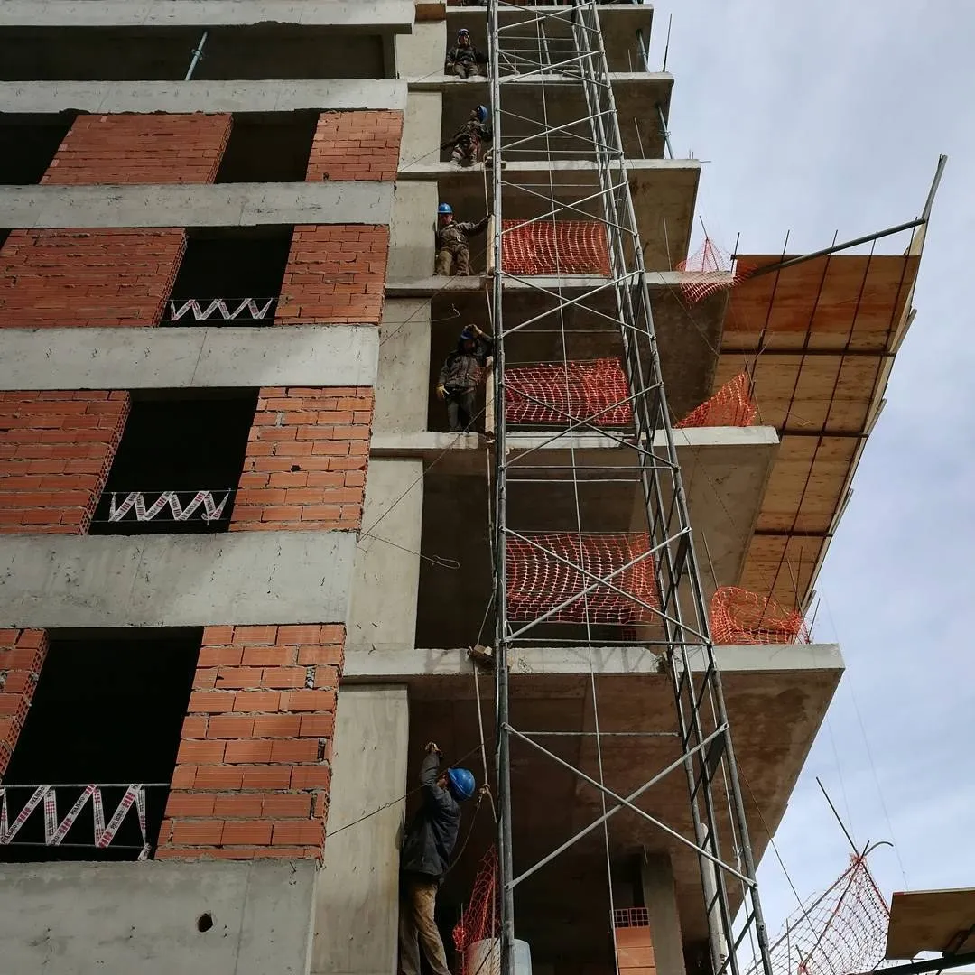 Operarios con casco trabajando en altura en una obra en construcción